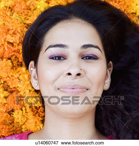 Stock Photo - Portrait of a young woman lying on Marigolds. Fotosearch
