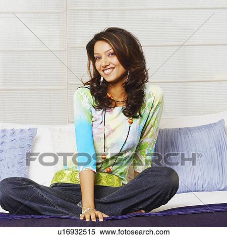Stock Photography - Portrait of a young woman sitting on the bed. Fotosearch