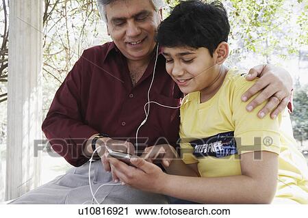 Close-up of a mature man and his grandson looking at an MP3 player View Large Photo Image Stock Image - Close-up of a mature man and his grandson looking at an MP3 player. Fotosearch