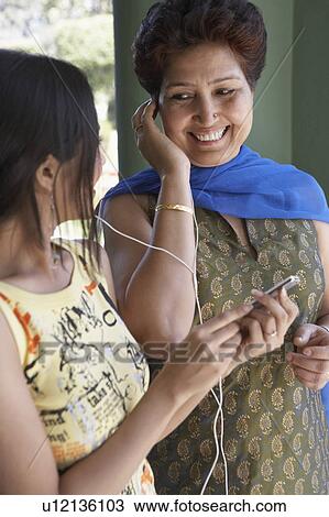 Close-up of a mature woman and her daughter listening to an MP3 player View Large Photo Image Stock Image - Close-up of a mature woman and her daughter listening to an MP3 player. Fotosearch