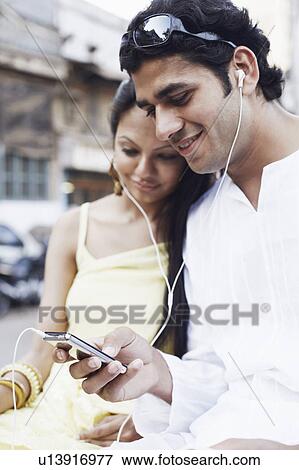 Stock Photo - Close-up of a young couple listening to an MP3 player. Fotosearch
