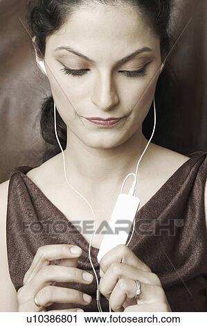Stock Image - Close-up of a young woman listening to an MP3 player. Fotosearch