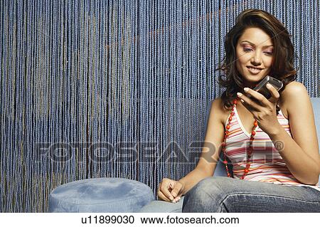 Stock Image - Close-up of a young woman looking at a mobile phone. Fotosearch