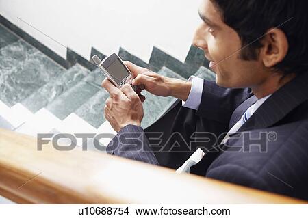 Picture - High angle view of a businessman holding a mobile phone. Fotosearch