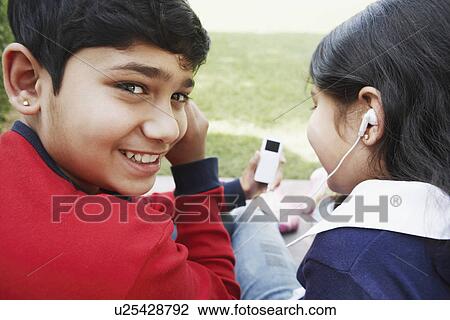 Stock Image - Portrait of a boy and his sister listening to an MP3 player. Fotosearch