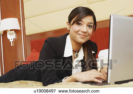 Portrait of a businesswoman lying on the bed and using a laptop View Large Photo Image Stock Photo - Portrait of a businesswoman lying on the bed and using a laptop. Fotosearch