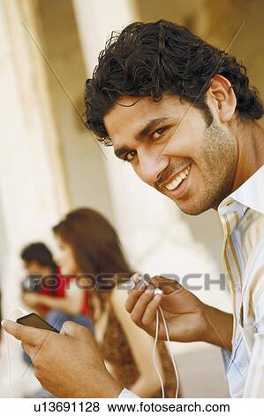 Portrait of a young man holding an MP3 player and smiling, Agra Fort, Agra, Uttar Pradesh, India View Large Photo Image Stock Photo - Portrait of a young man holding an MP3 player and smiling, Agra Fort, Agra, Uttar Pradesh, India. Fotosearch