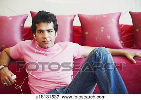 Stock Photo - Portrait of a young man listening to music on an MP3 player. Fotosearch