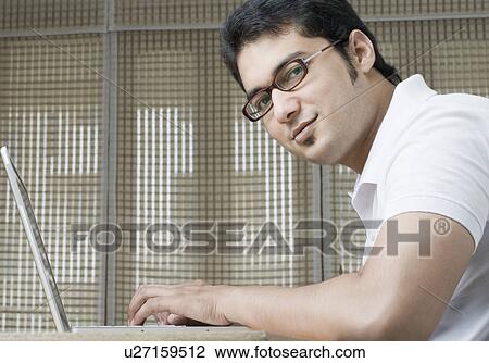 Stock Image - Portrait of a young man using a laptop. Fotosearch