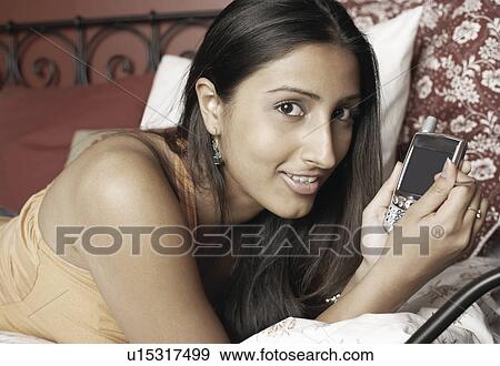 Stock Photo - Portrait of a young woman holding a mobile phone. Fotosearch