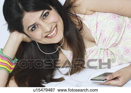 Portrait of a young woman listening to an MP3 player View Large Photo Image Stock Photo - Portrait of a young woman listening to an MP3 player. Fotosearch
