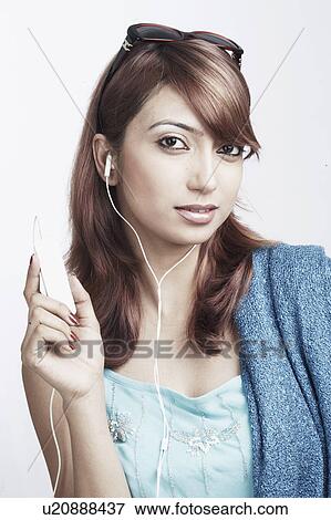 Stock Photo - Portrait of a young woman listening to an MP3 player. Fotosearch