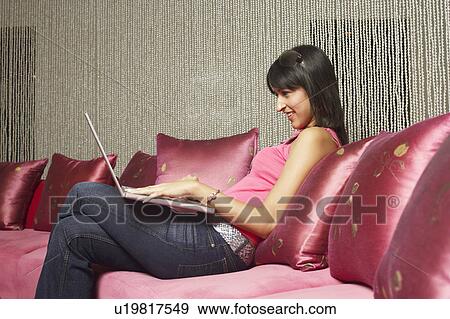 Stock Photo - Side profile of a young woman using a laptop. Fotosearch