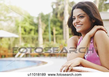 Stock Photo - Close-up of a young woman smiling with her hand on her shoulder. Fotosearch