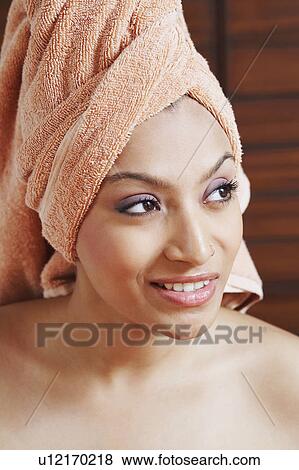 Stock Photo - Close-up of a young woman with a towel wrapped around her hair and smiling. Fotosearch