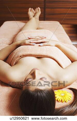 High angle view of a young woman lying on a massage table View Large Photo Image Stock Image - High angle view of a young woman lying on a massage table. Fotosearch