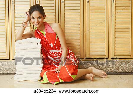 Portrait of a young woman leaning over a stack of towels and smiling View Large Photo Image Picture - Portrait of a young woman leaning over a stack of towels and smiling. Fotosearch