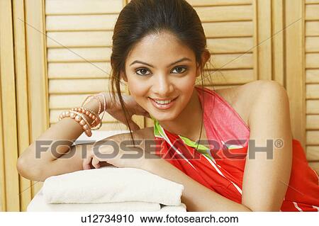 Portrait of a young woman leaning over a stack of towels and smiling View Large Photo Image Stock Image - Portrait of a young woman leaning over a stack of towels and smiling. Fotosearch