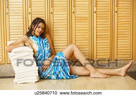 Portrait of a young woman leaning over a stack of towels in a locker room View Large Photo Image Stock Image - Portrait of a young woman leaning over a stack of towels in a locker room. Fotosearch