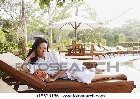 Stock Photograph - Portrait of a young woman lying on a lounge chair. Fotosearch