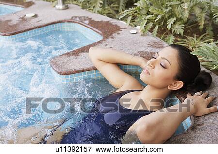 Stock Photo - Young woman lying in a swimming pool with her eyes closed. Fotosearch