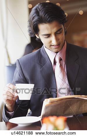 Stock Photo - Businessman holding a cup of tea and reading a newspaper. Fotosearch