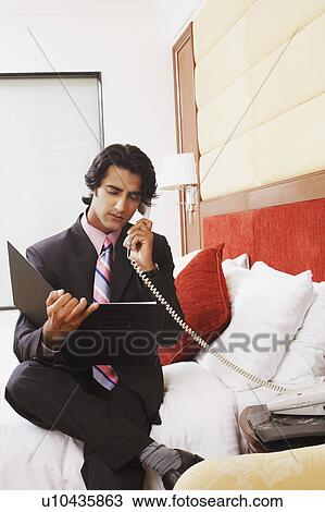 Stock Image - Businessman talking on the telephone and reading a file. Fotosearch