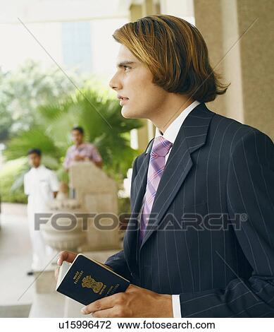 Stock Image - Close-up of a businessman holding a passport. Fotosearch