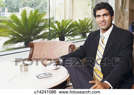 Close-up of a businessman sitting in a cafeteria View Large Photo Image Stock Photograph - Close-up of a businessman sitting in a cafeteria. Fotosearch