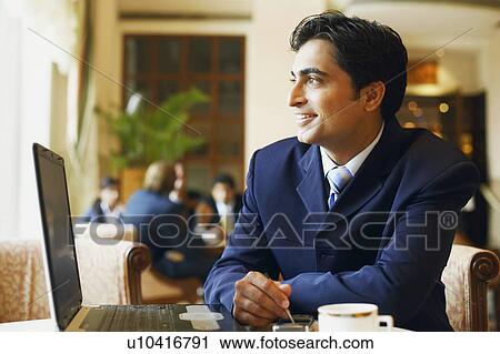 Stock Image - Close-up of a businessman using a mobile phone in a cafeteria. Fotosearch