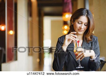 Stock Image - Close-up of a young woman holding a glass of pinacolada. Fotosearch