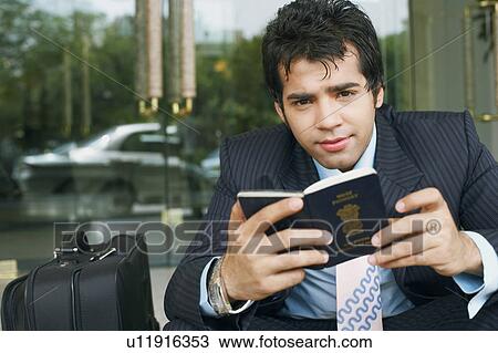 Stock Image - Portrait of a businessman holding a passport. Fotosearch