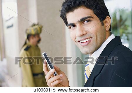 Portrait of a businessman holding a mobile phone and smiling View Large Photo Image Stock Photography - Portrait of a businessman holding a mobile phone and smiling. Fotosearch