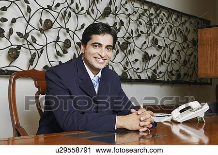 Stock Image - Portrait of a businessman smiling with his hands clasped. Fotosearch