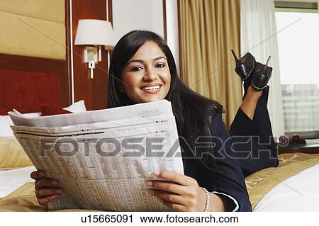 Portrait of a businesswoman lying on the bed and holding a newspaper View Large Photo Image Stock Image - Portrait of a businesswoman lying on the bed and holding a newspaper. Fotosearch