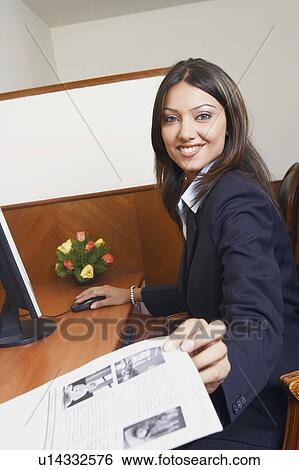 Portrait of a businesswoman working on a computer and holding a sheet of paper View Large Photo Image Stock Photograph - Portrait of a businesswoman working on a computer and holding a sheet of paper. Fotosearch