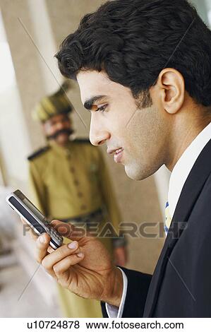 Stock Photo - Side profile of a businessman using a mobile phone. Fotosearch