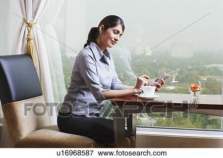 Stock Photo - Side profile of a businesswoman operating a mobile phone. Fotosearch