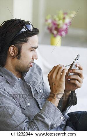 Side profile of a young man using a mobile phone with a digitized pen View Large Photo Image Picture - Side profile of a young man using a mobile phone with a digitized pen. Fotosearch