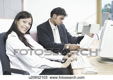 Businessman and a businesswoman sitting in an office View Large Photo Image Stock Image - Businessman and a businesswoman sitting in an office. Fotosearch