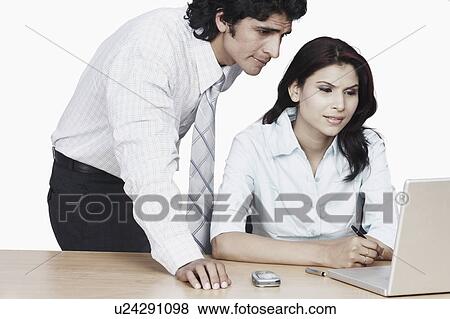Stock Photo - Businessman and a businesswoman using a laptop. Fotosearch