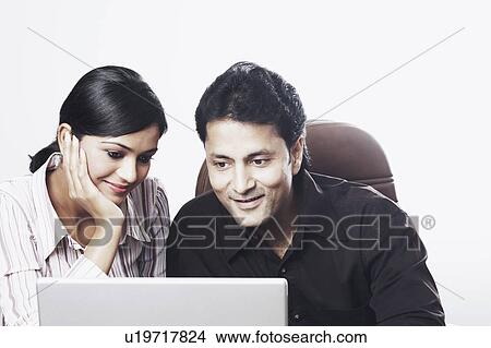 Picture - Close-up of a businessman and a businesswoman working on a laptop. Fotosearch