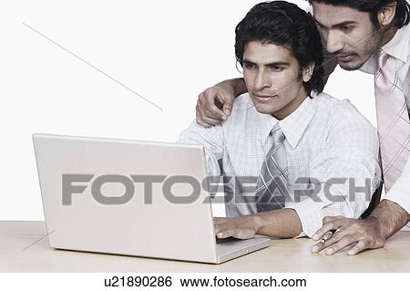 Stock Photograph - Close-up of two businessmen using a laptop. Fotosearch
