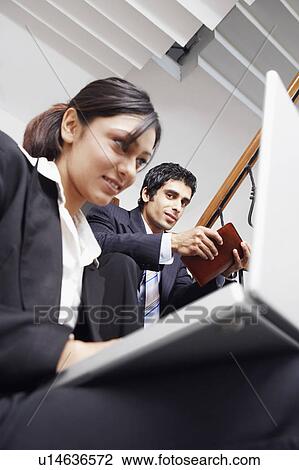 Low angle view of a businesswoman using a laptop with a businessman holding a personal organizer View Large Photo Image Stock Image - Low angle view of a businesswoman using a laptop with a businessman holding a personal organizer. Fotosearch