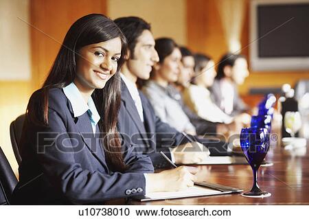 Portrait of a businesswoman sitting with her colleagues in a conference room and smiling View Large Photo Image Stock Image - Portrait of a businesswoman sitting with her colleagues in a conference room and smiling. Fotosearch