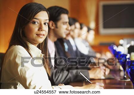 Portrait of a businesswoman sitting with her colleagues in a conference room View Large Photo Image Stock Photo - Portrait of a businesswoman sitting with her colleagues in a conference room. Fotosearch