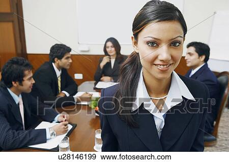 Stock Photo - Portrait of a businesswoman with four business executives sitting behind her. Fotosearch