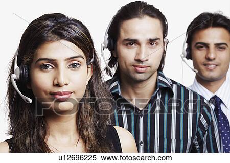 Stock Photography - Portrait of a young woman and two young men wearing headsets in a row. Fotosearch