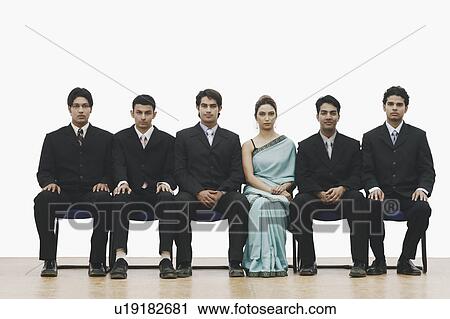 Stock Image - Portrait of a young woman sitting between five young men. Fotosearch
