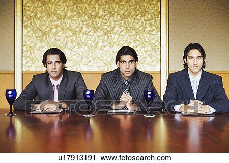 Stock Image - Portrait of three businessmen sitting in a conference room. Fotosearch